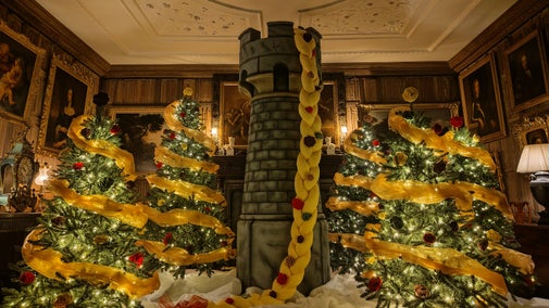 In a festive display a tower with Rapunzel's long blonde plait sits between sparkling Christmas trees in the Dining Parlour at The Vyne.